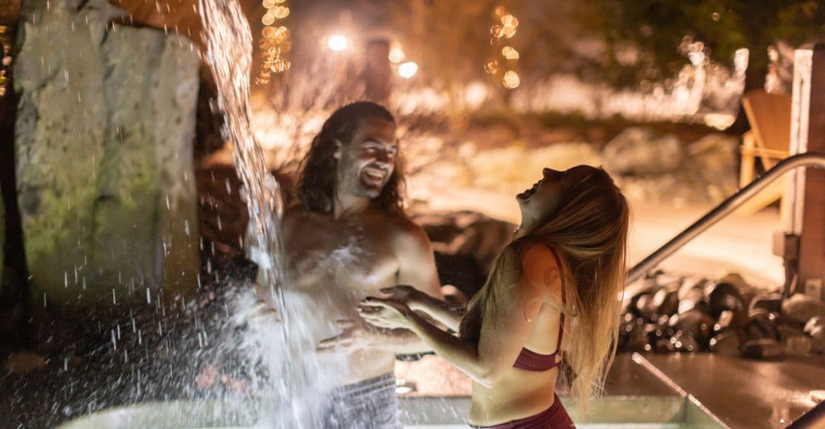 Un couple sous la chute froide au spa nordique Scandinave Spa Whistler.