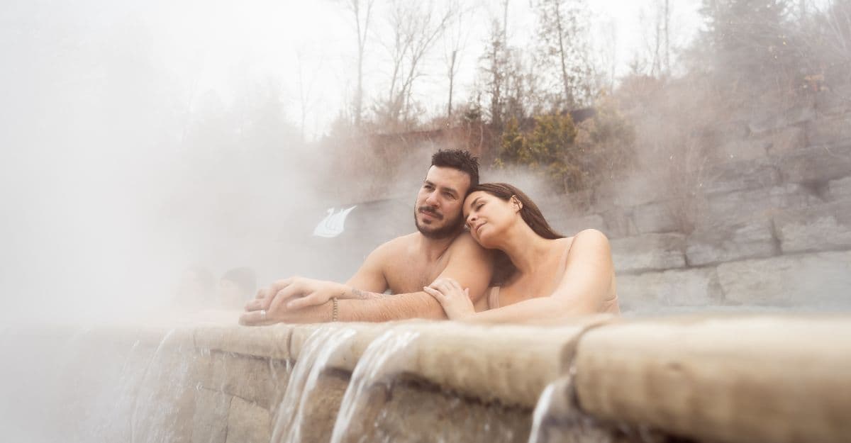A couple relaxes in an outdoor hot pool at the nordic spa Scandinave Spa Mont-Tremblant.