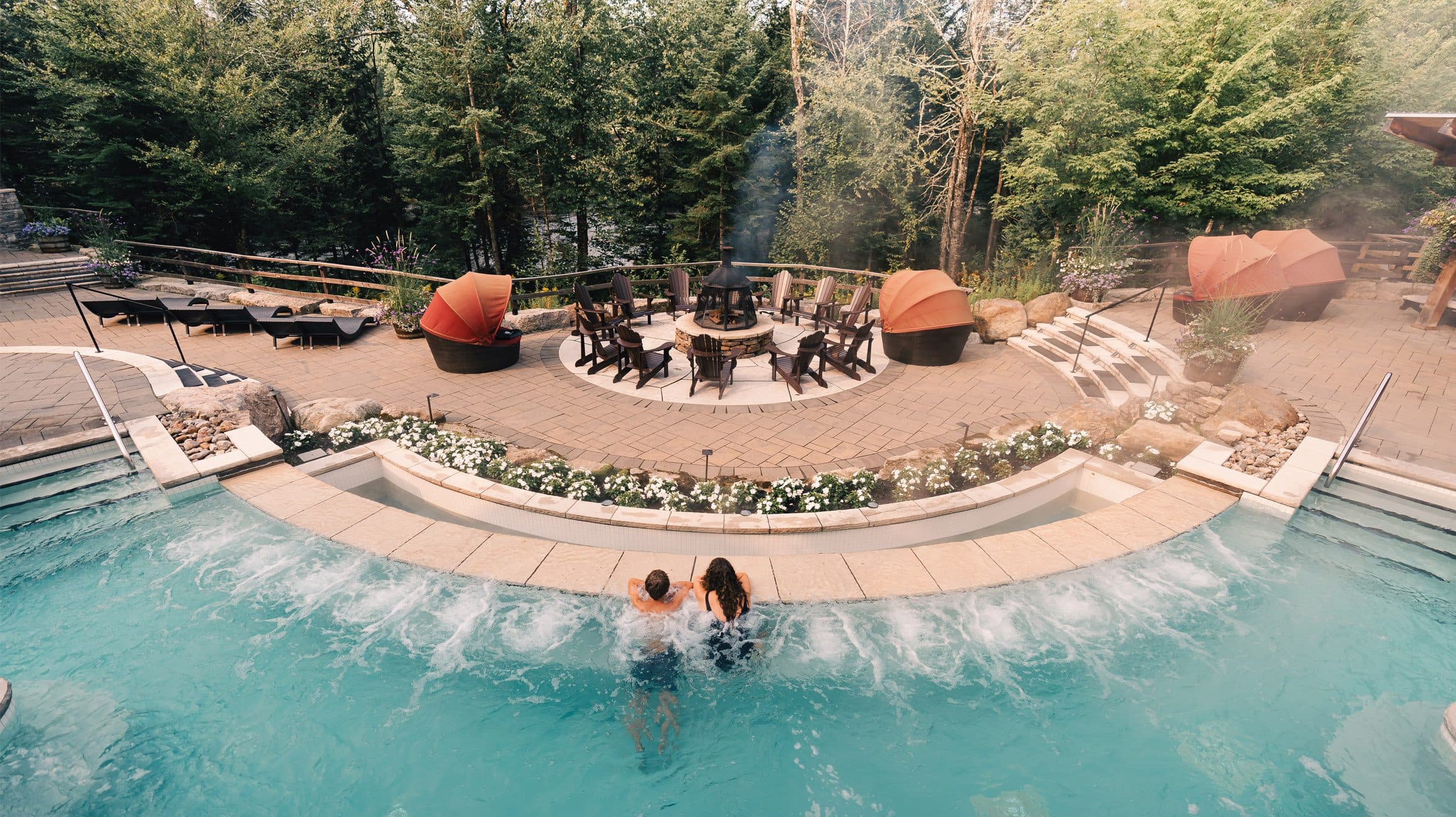 A couple relaxing in the infinity pool, the largest hot bath installation at Scandinave Spa Mont-Tremblant.