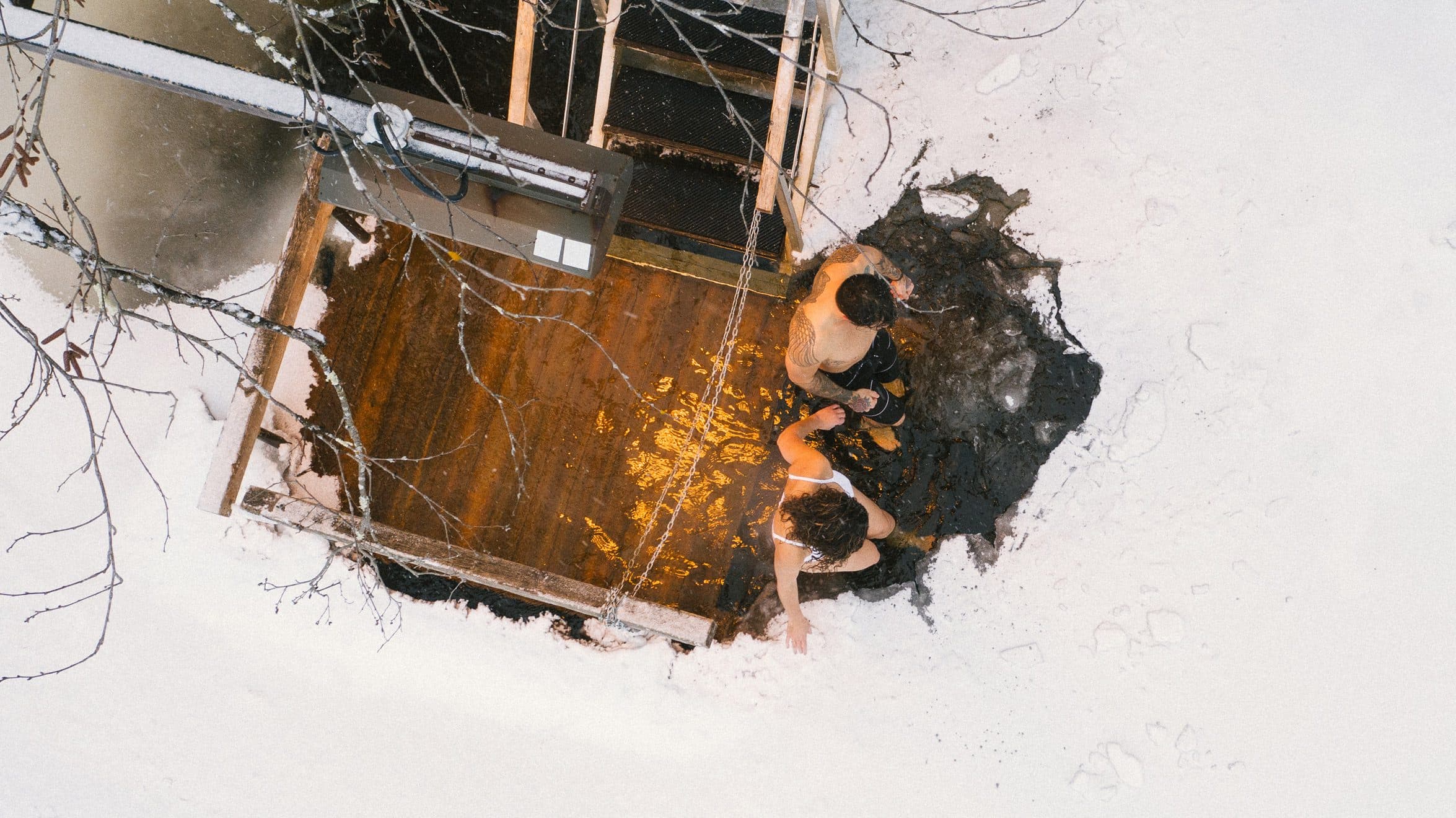 A couple experiences the cold plunge in the winter waters of the Diable River at Scandinave Spa Mont-Tremblant.