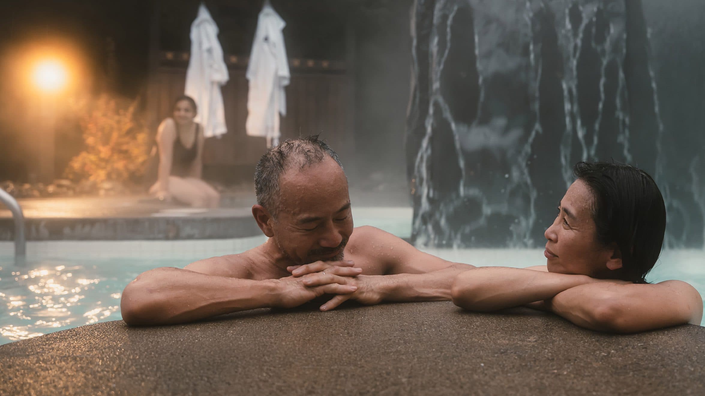 Couple relaxing in outdoor hot baths at Scandinave Spa, enjoying the serene surroundings.