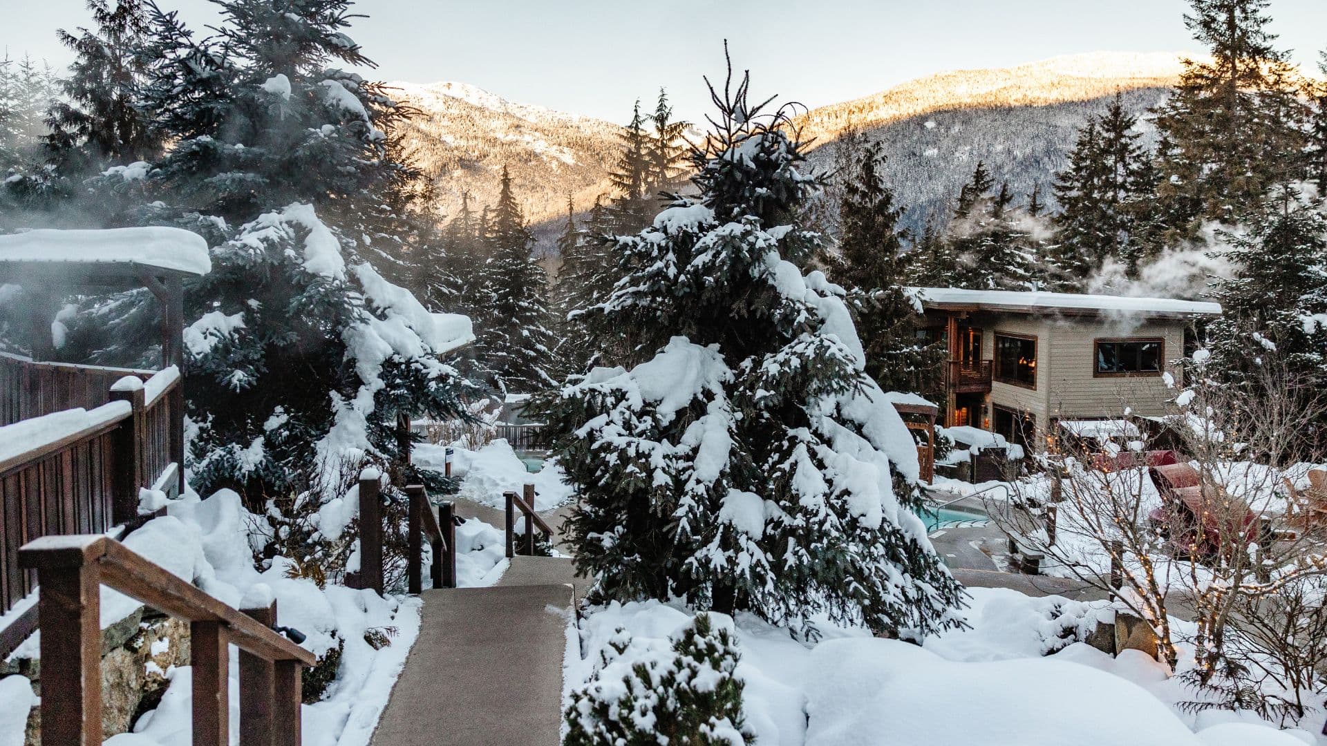 Spa extérieur enneigé niché dans une zone boisée et montagneuse.